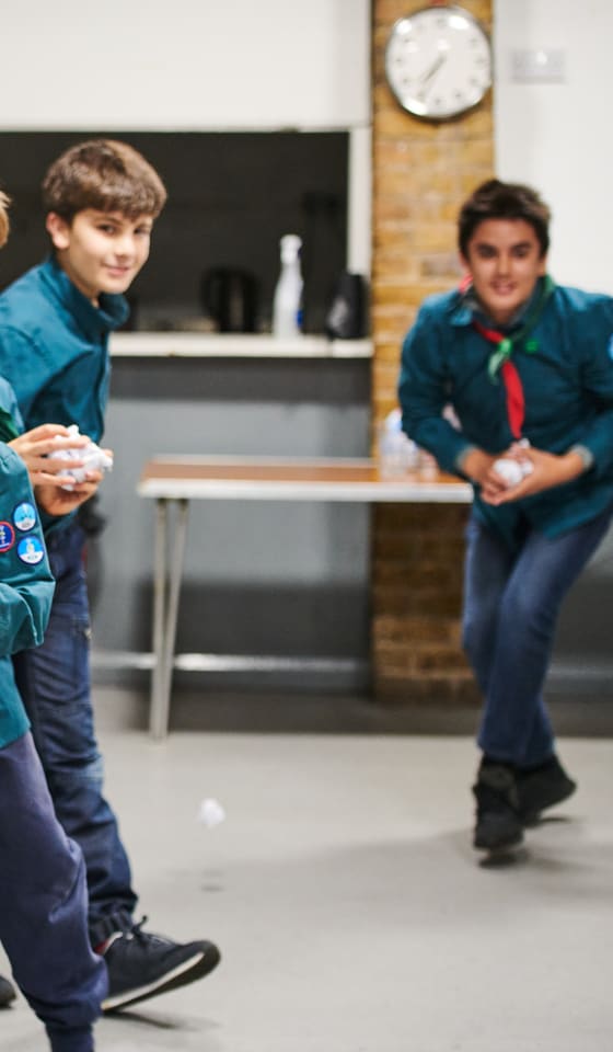 Scouts throwing paper snowballs across their meeting hall.